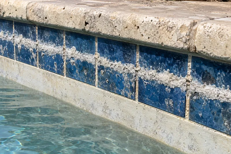 White calcium scale line on blue waterline tile
