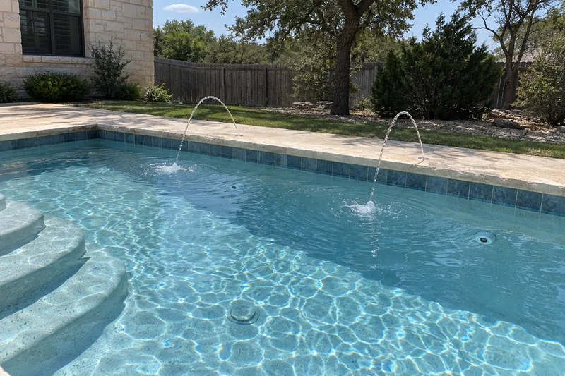 Deck jets arcing streams of water into a backyard pool