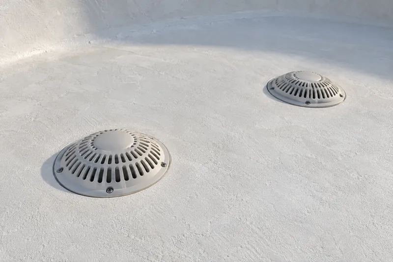 Two domed drain covers set in a fresh white pool finish