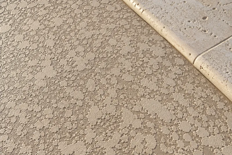 Close-up of a knockdown deck coating beside pool coping